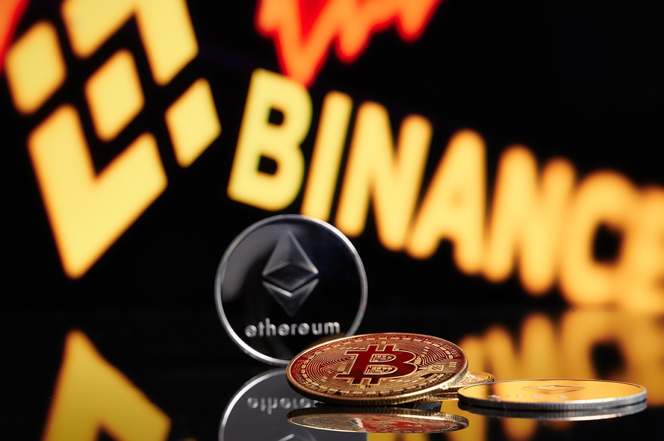 A stack of crypto coins in front of a Binance logo.