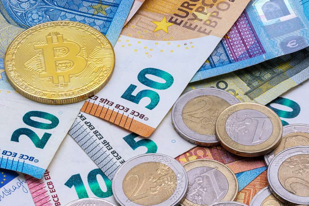 Bitcoin and Euro banknotes and coins.